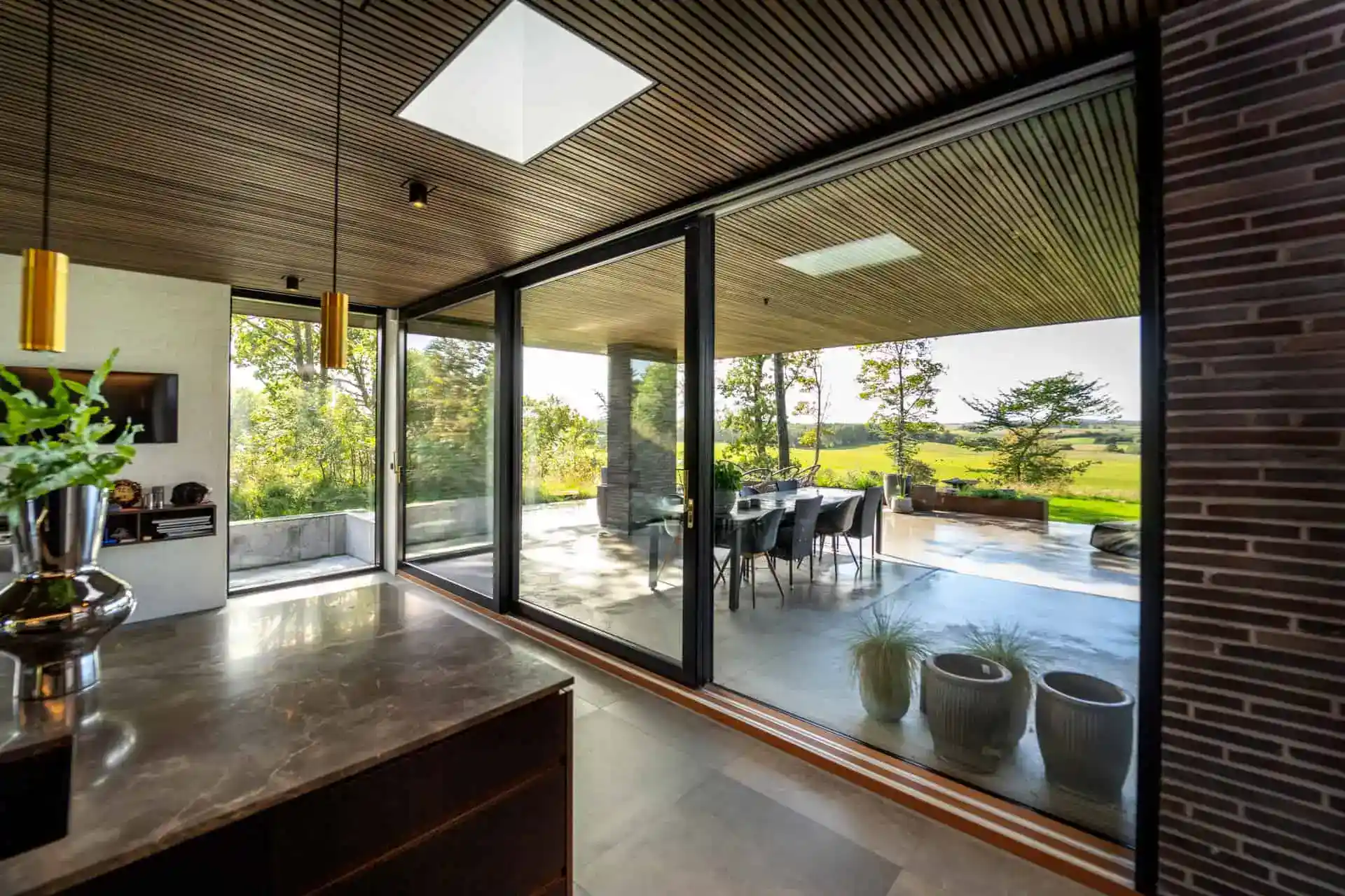 Særlig store glaspartier med udsigt over grønne marker og træer.