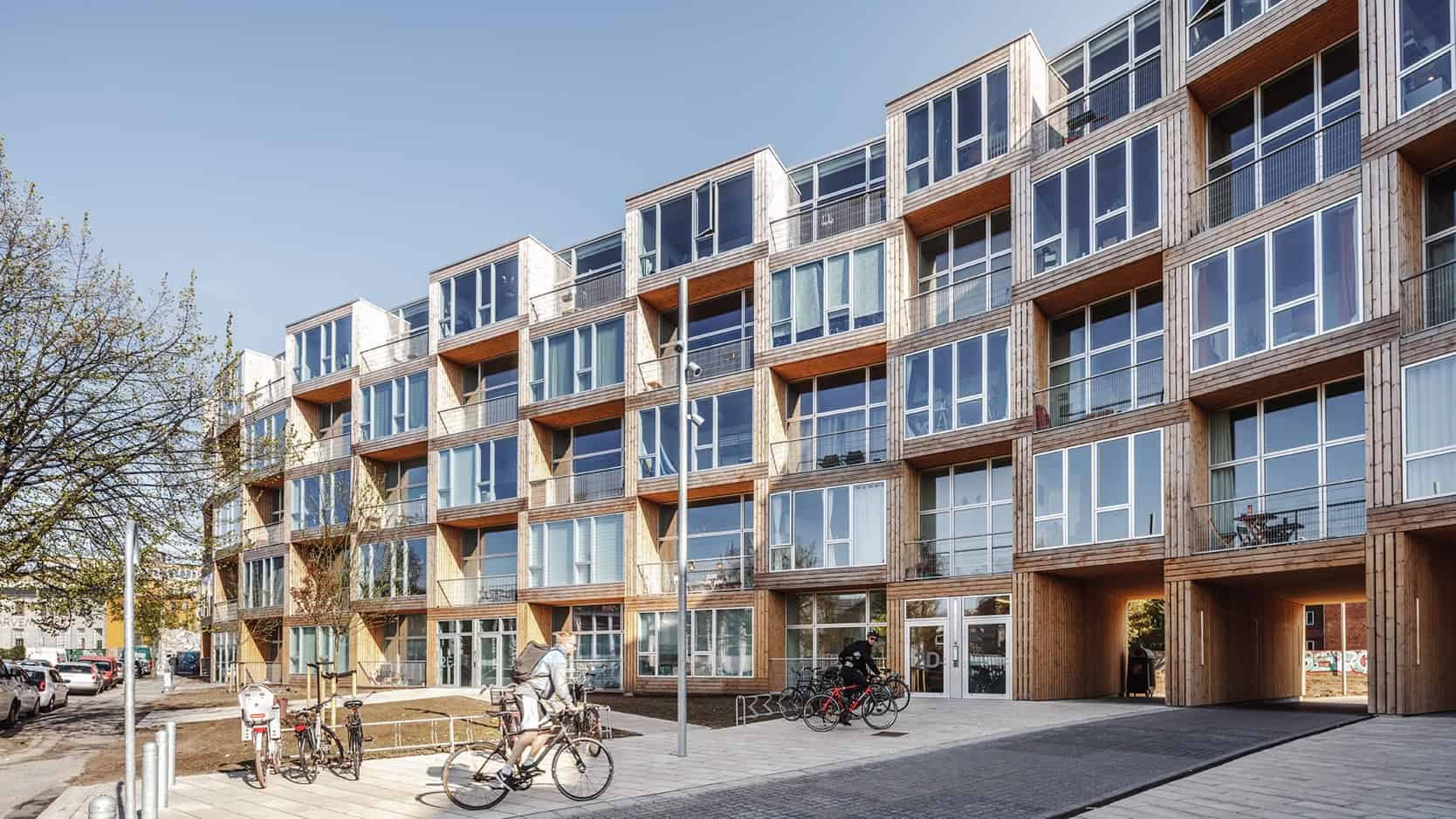 Elegant træfacade med store vinduespartier i moderne boligkompleks.