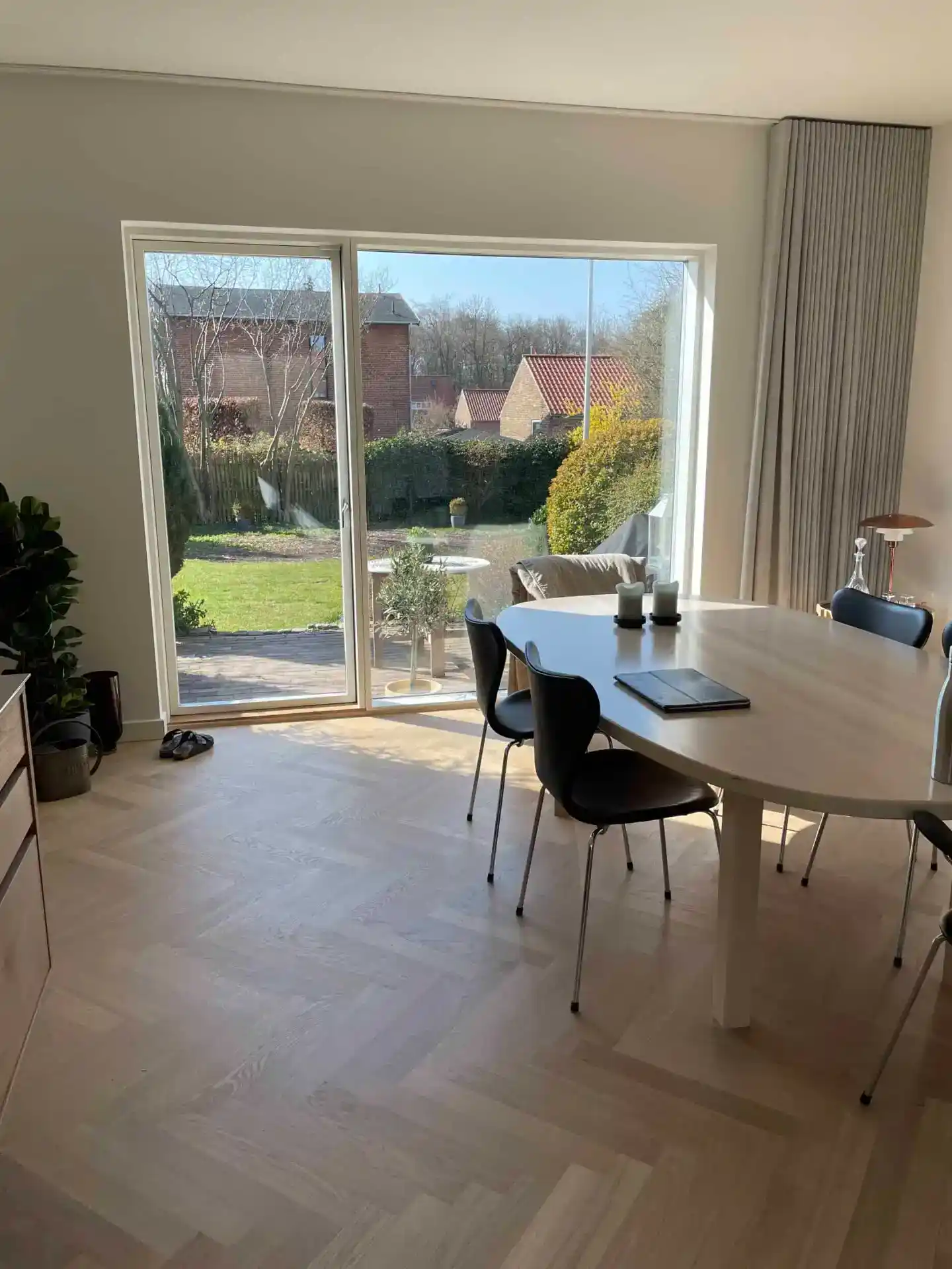 Hjørne af moderne glaskarnindus med udsigt over have og huse.