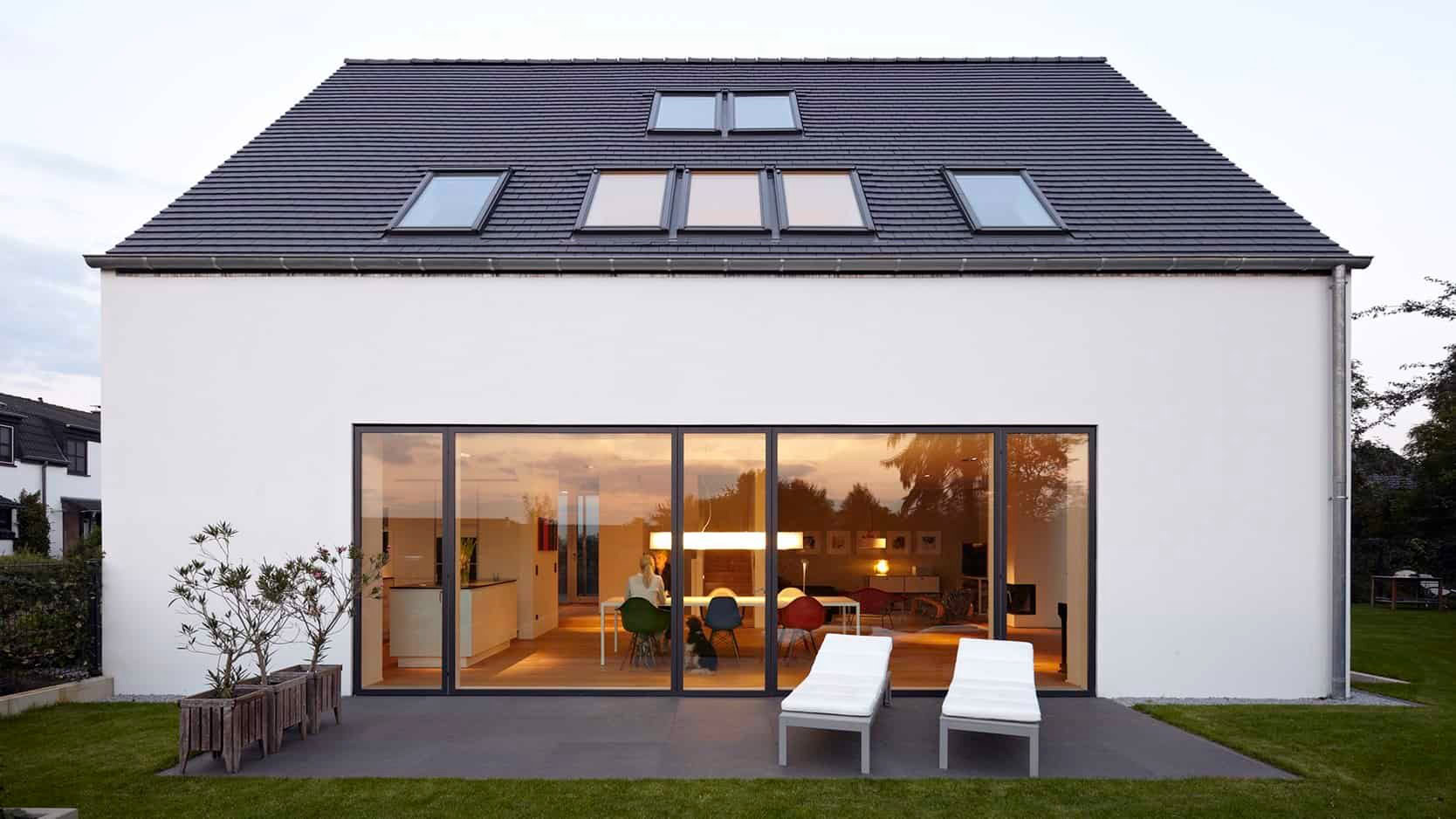 Elegant moderne vinduer og glasdøre foran et lyst hus med have.