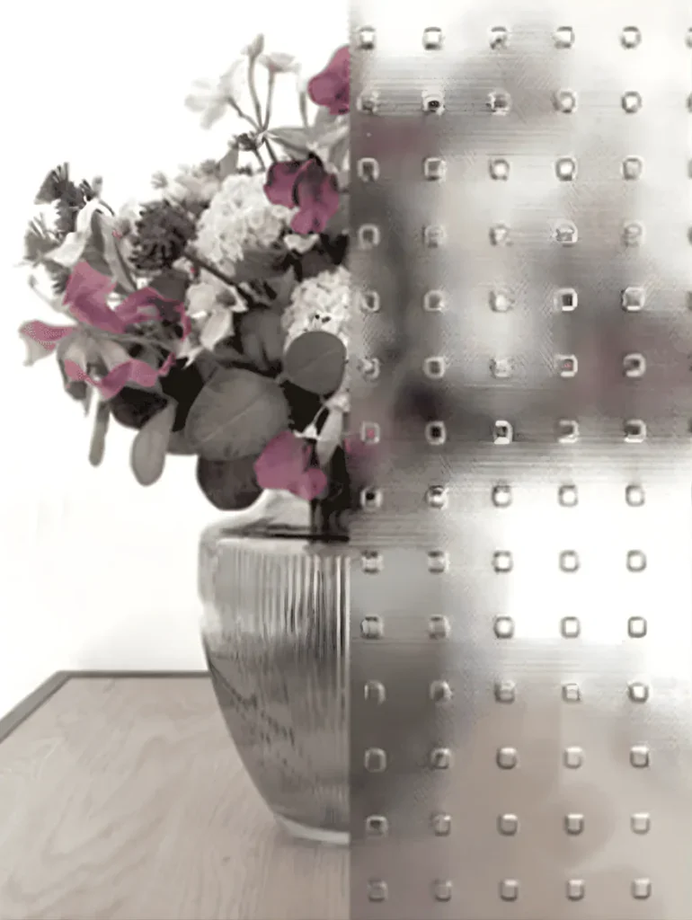 Farvet blomsterbuket i en keramisk vase på et træbord.