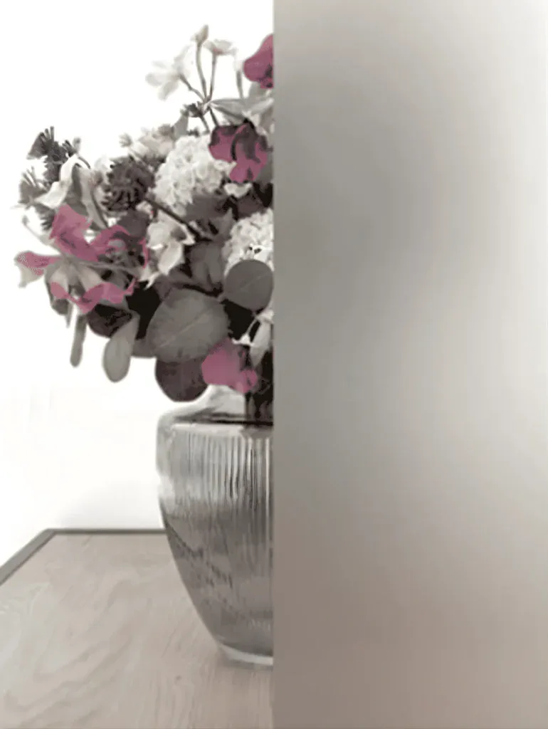 Farvet blomsterdekoration i glasvase på stuebord.