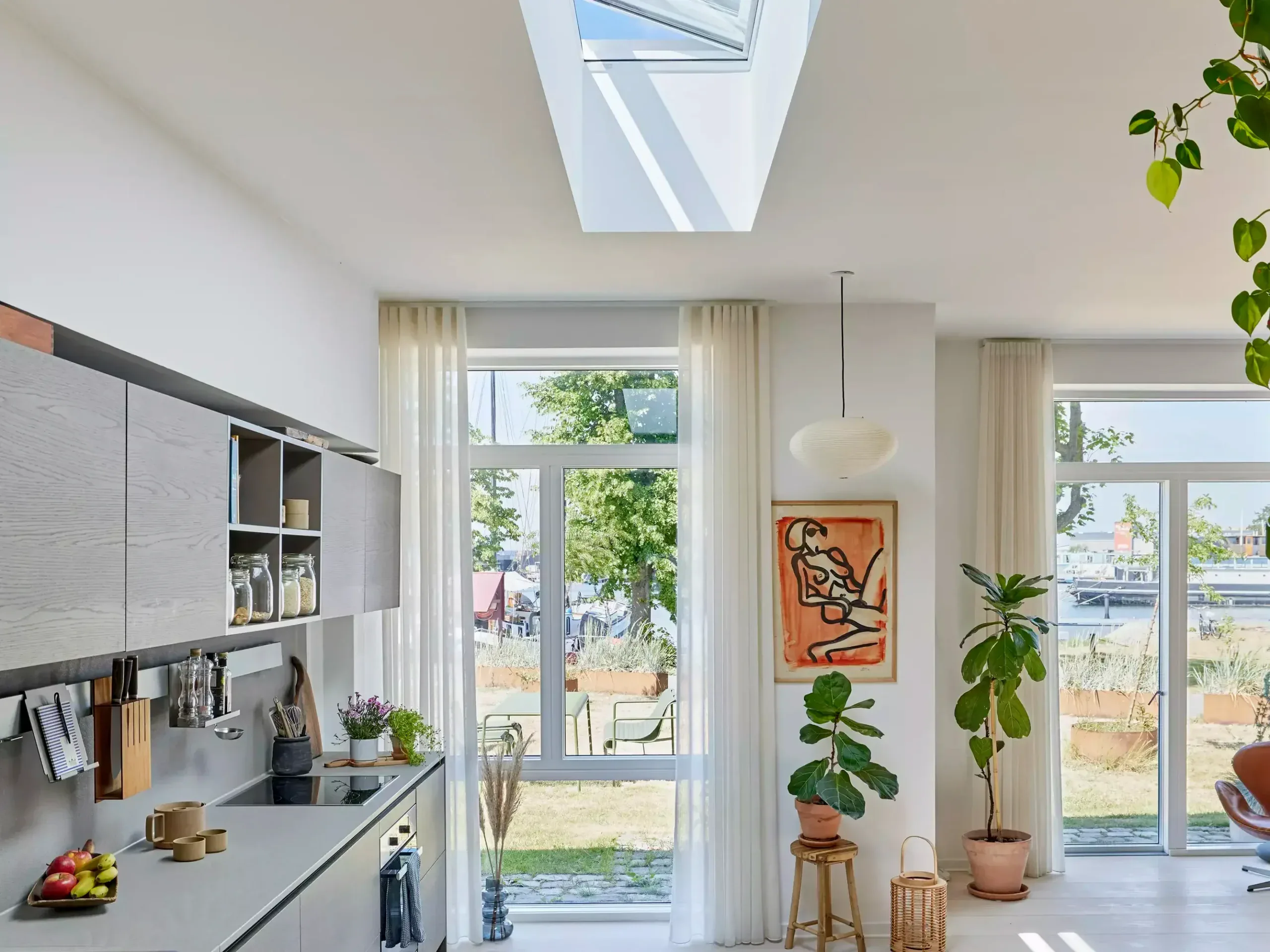 Elegant stort vindue med udsigt over haven, lysindfald og moderne boligindretning.