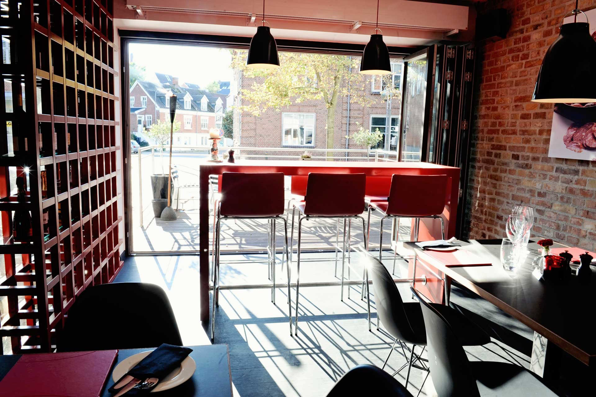 Lyst indendørs restaurant med store vinduer og moderne design.