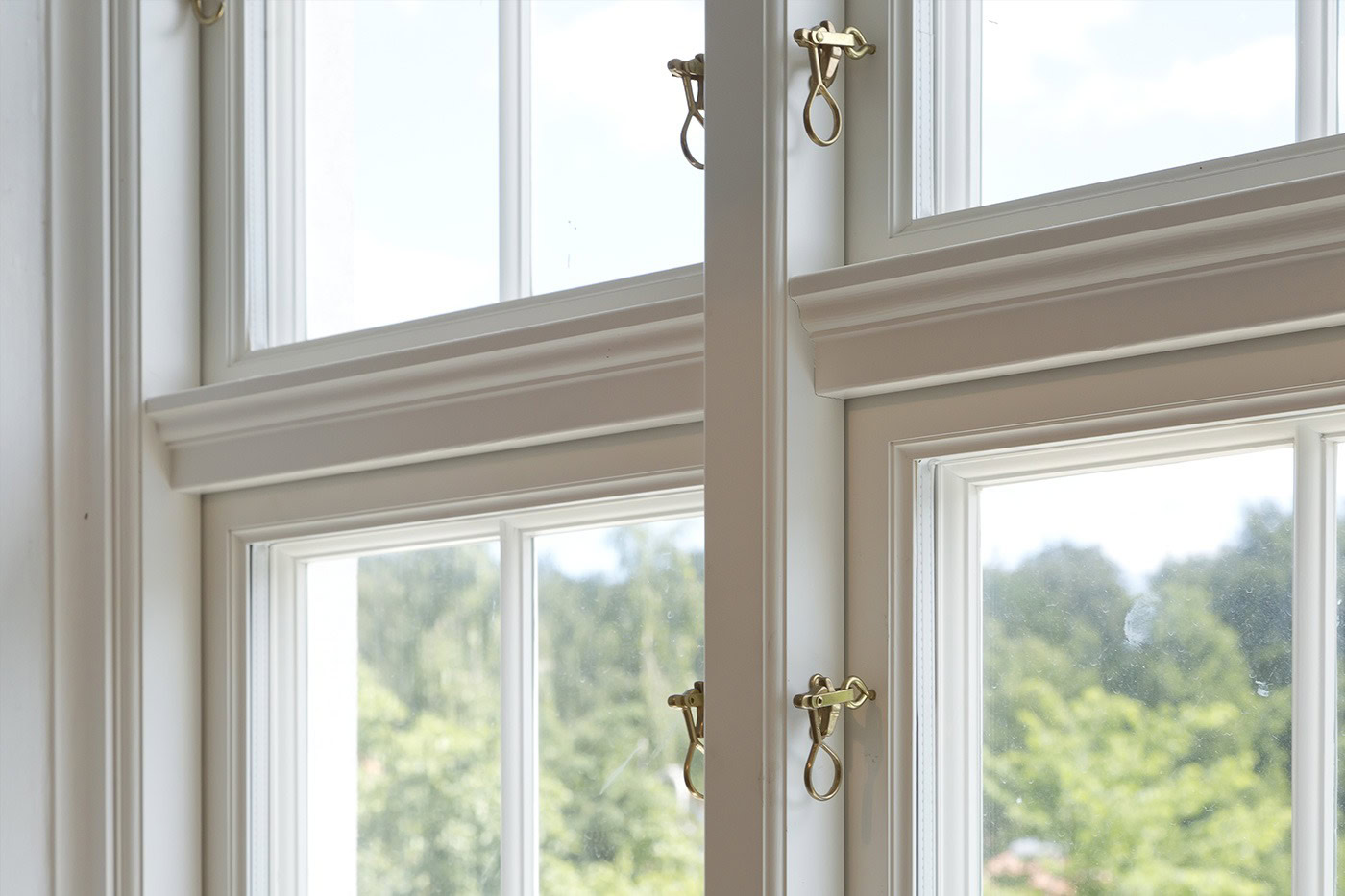 Hvidt trævindue med flere paneler og gyldne håndtag, perfekt til klassiske hjem.