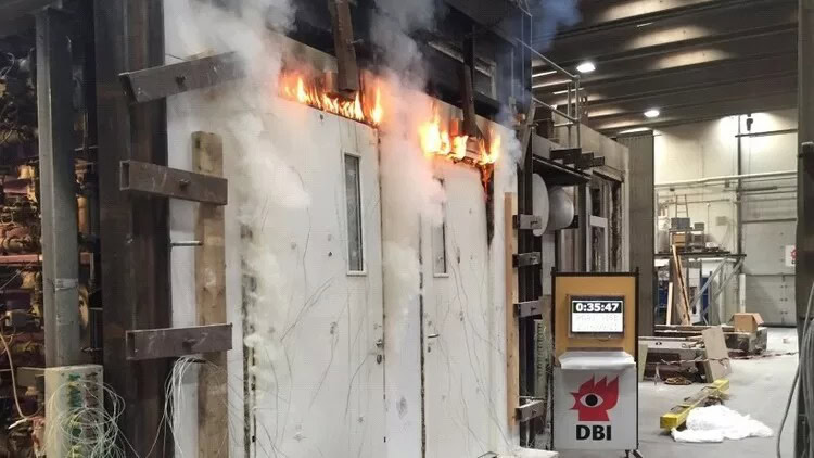 Brand i industrilokal med kraftig flamme og røg, potentiel fare for medarbejdere og strukturer.