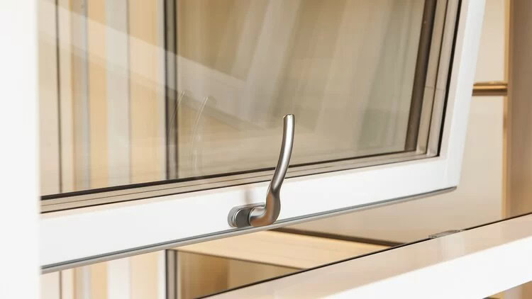 Håndtaget på moderne vindue med hvid ramme og gennemsigtigt glas.