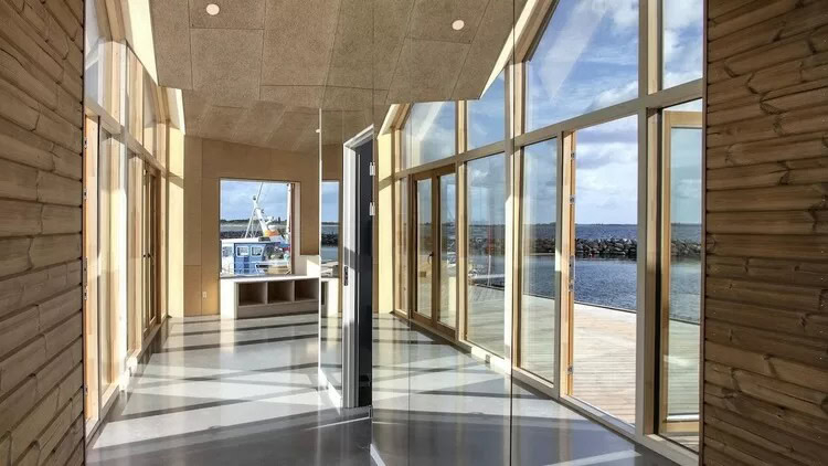 Klare, store vinduer i et moderne hus med udsigt over havet.