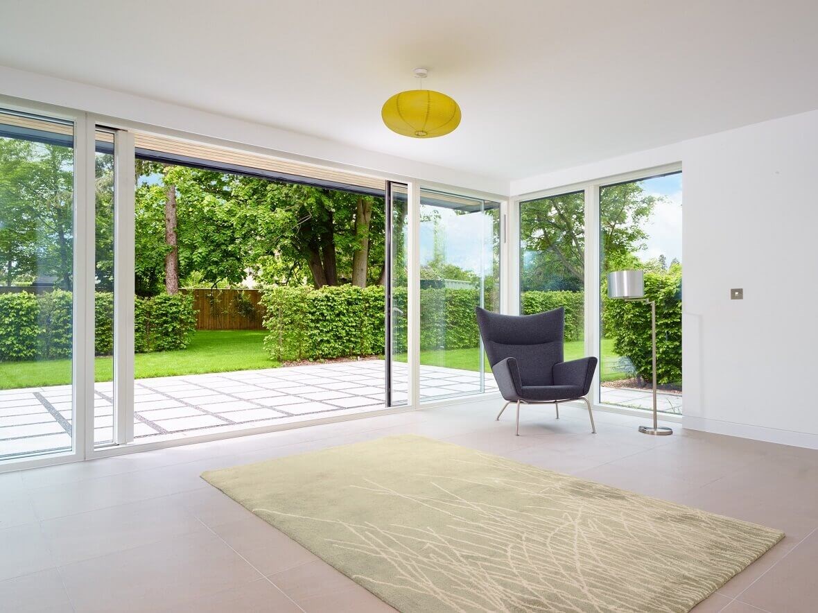 Energibesparende store glasdøre med udsigt til grønne omgivelser.